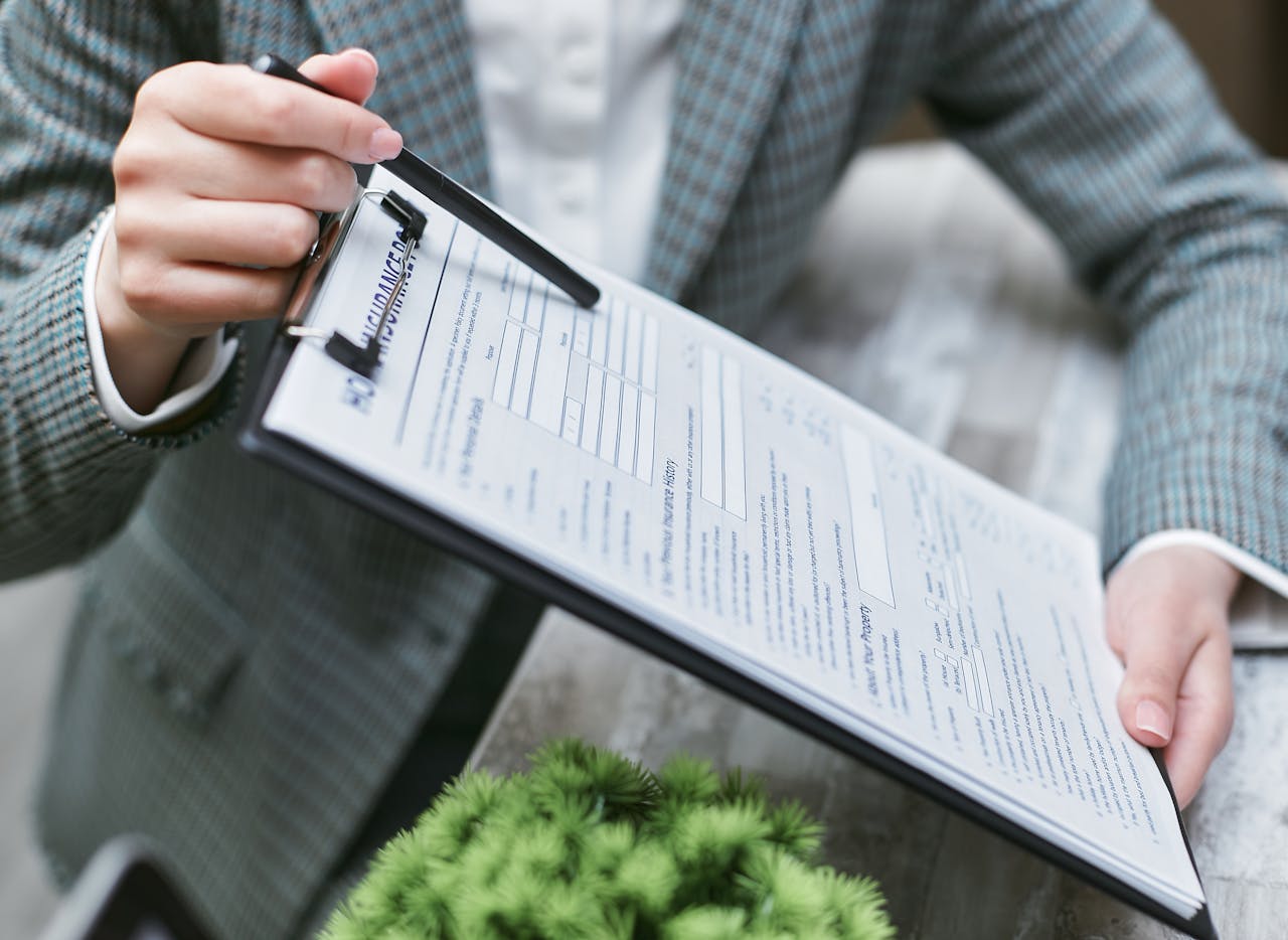 Close-up of a businessperson holding a clipboard with an insurance document, emphasizing details.